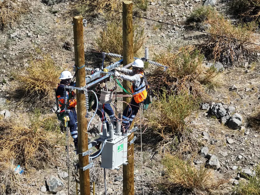 Dos linieros interviniendo el equipo de medida de una línea de 23 kV